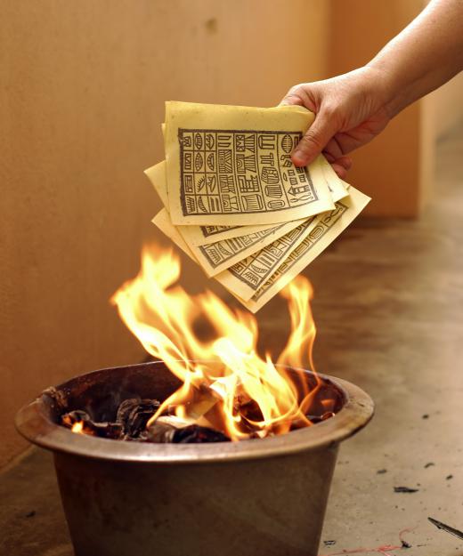 A person burning a facsimile of ancient Chinese money for a deceased couple.